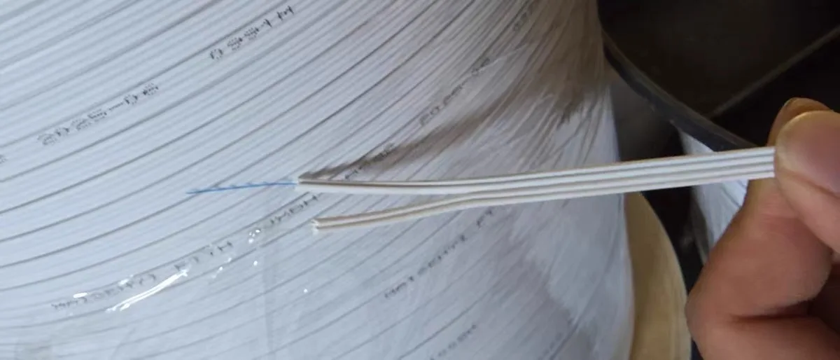 White flat indoor drop cable with exposed construction from the factory image library, not a fire-test or certification photograph